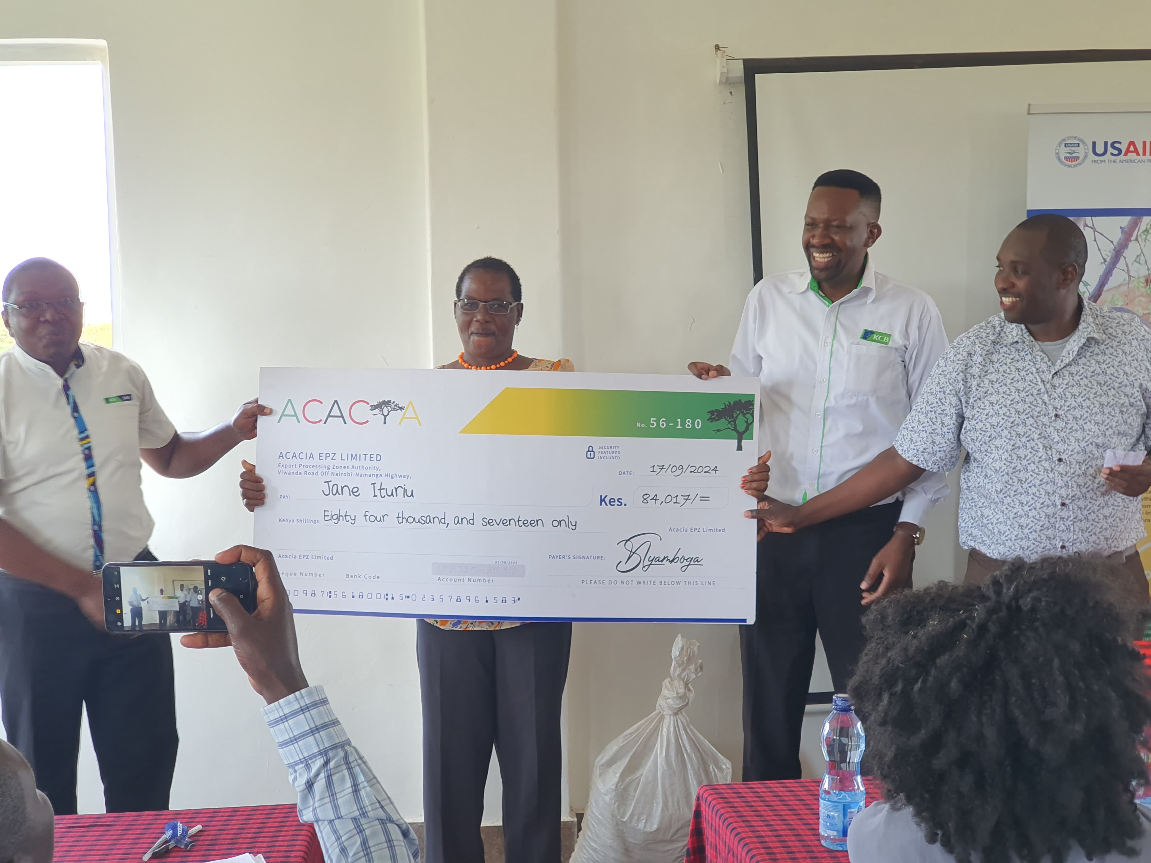Jane Ituriu receiving her Revolving Fund bonus cheque of KES 84,017